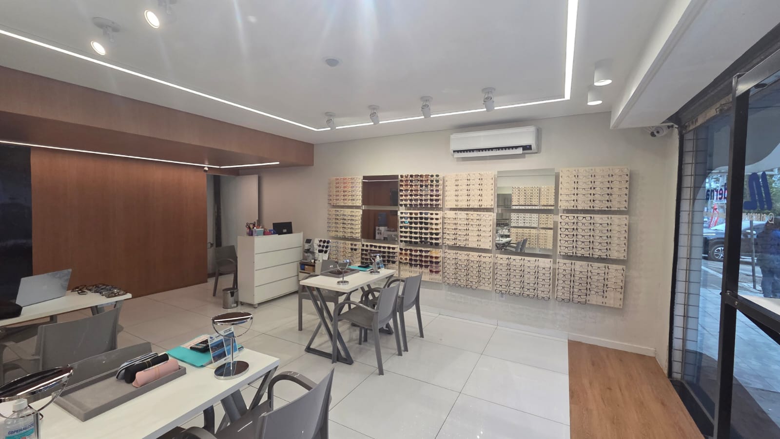 Interior da Ótica Moderna com mesas de atendimento e parede de armações
